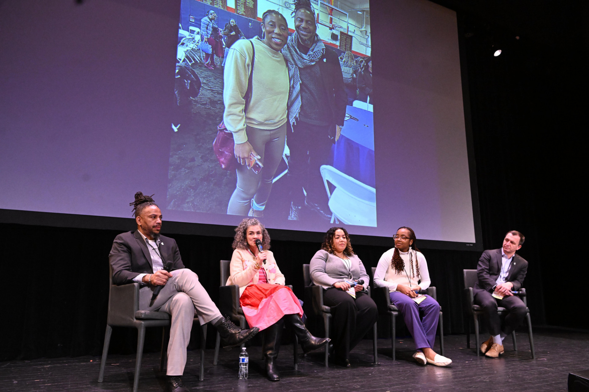 5 people sitting on a stage for a panel