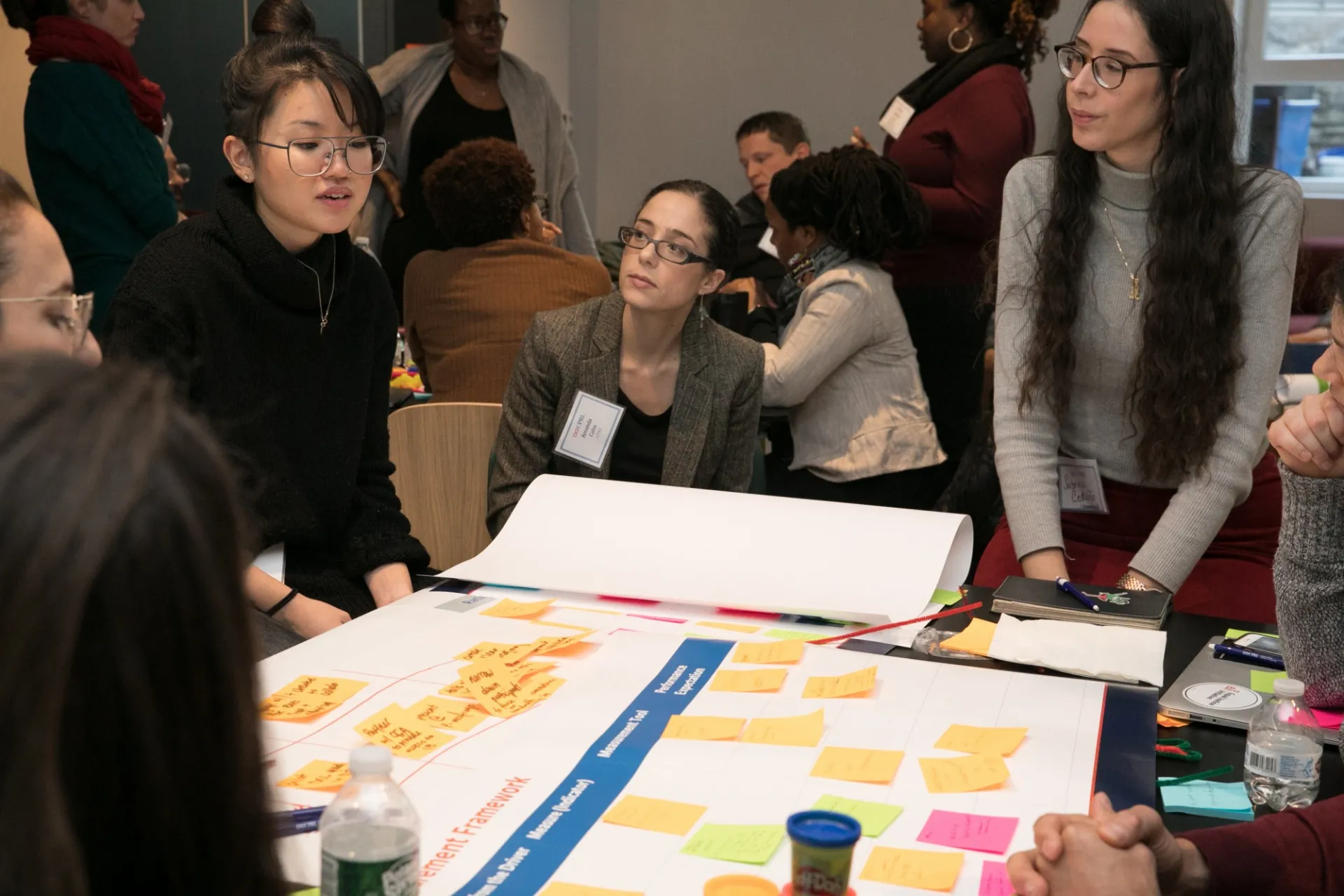 Participants seated and standing around chart paper on a table.