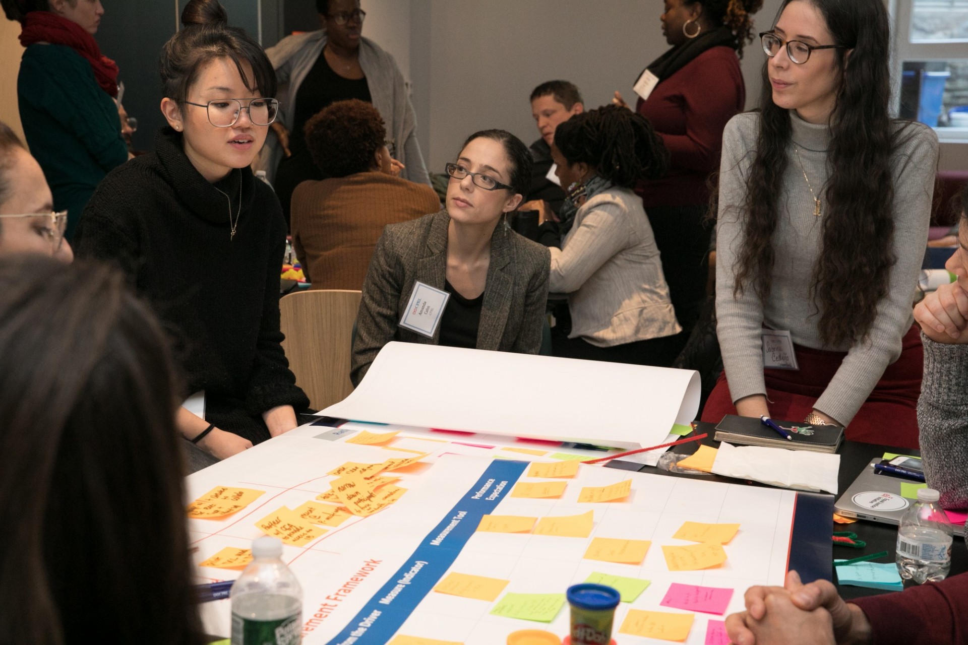 Participants seated and standing around chart paper on a table.