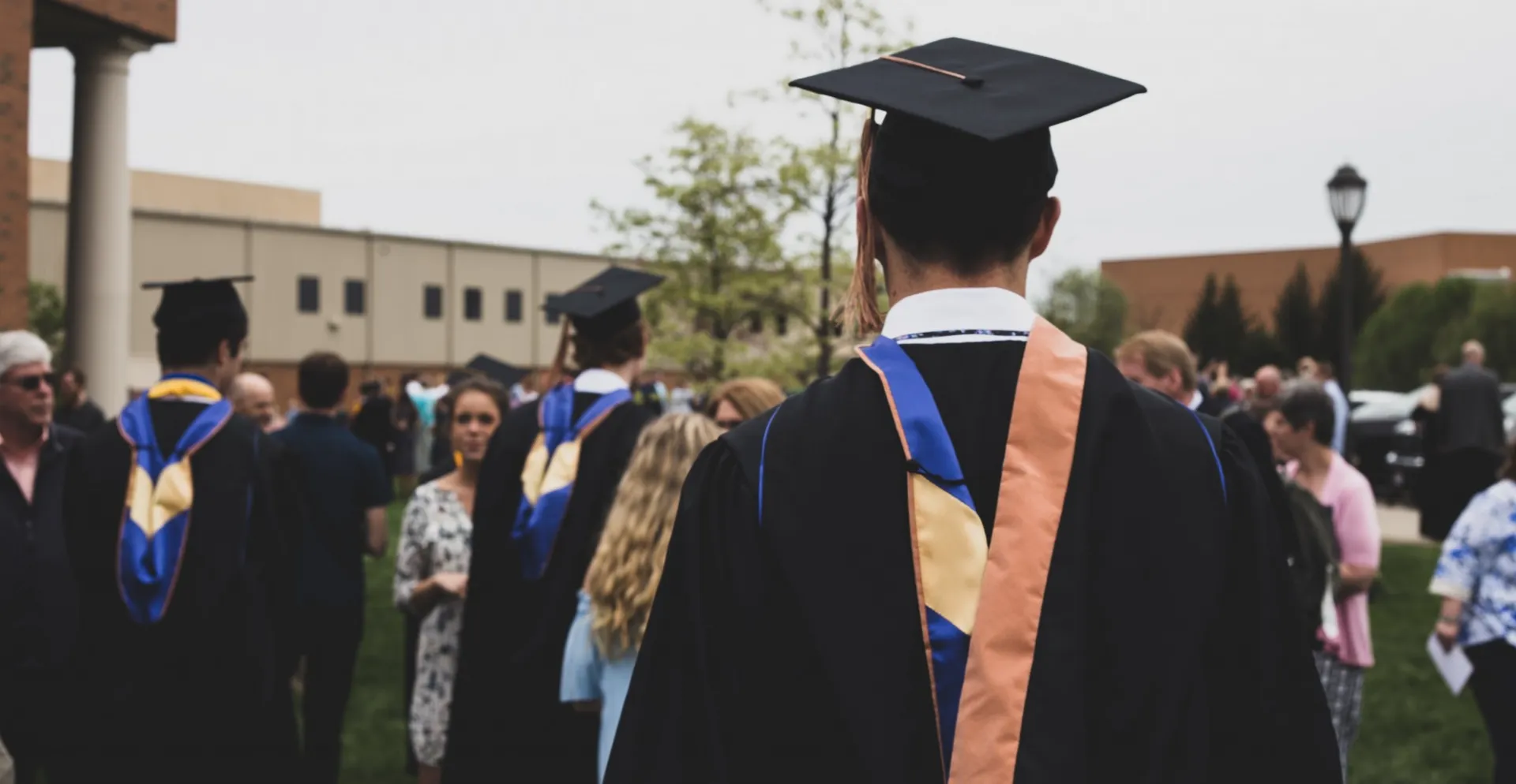 Young man with back to camera walking forward in graduation cap and gown
