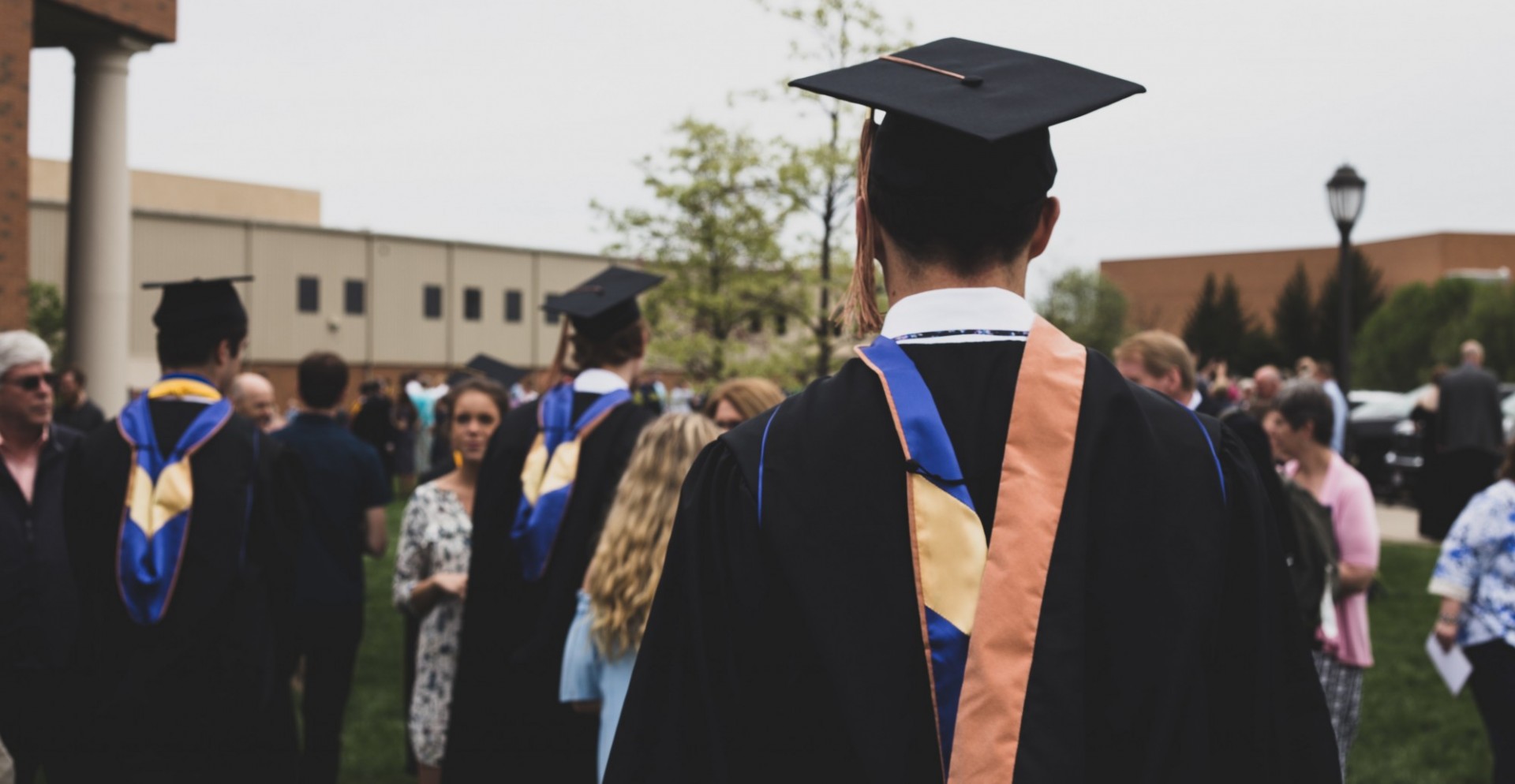 Young man with back to camera walking forward in graduation cap and gown