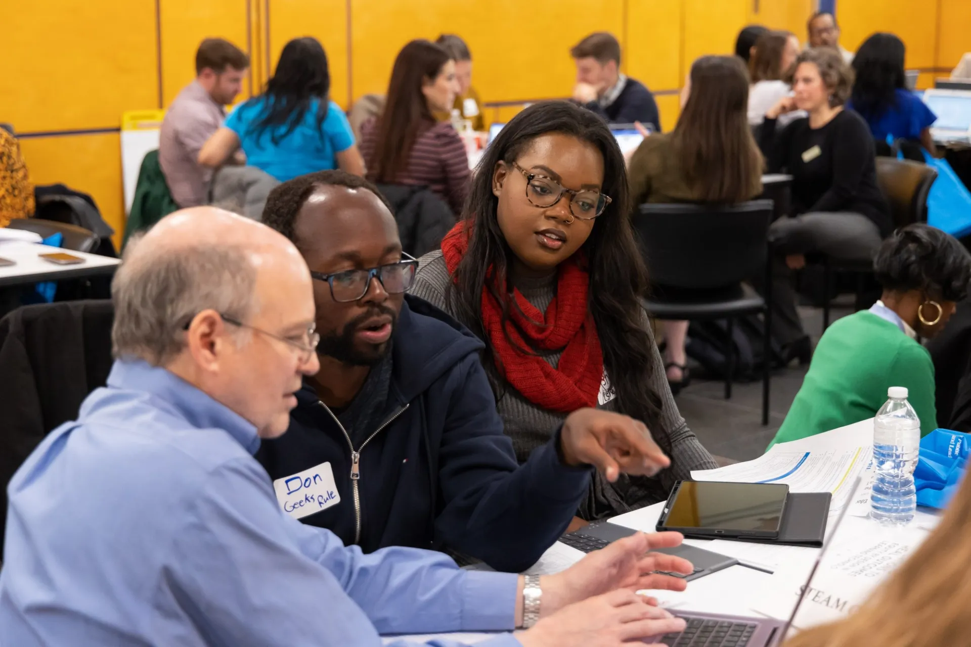 Educators talking at a laptop in a conference room. 