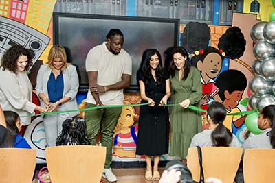 staff cut ribbon on a new school library, with students watching