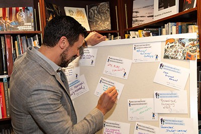 Man writing his thoughts on the future of education on CPRL's event activity board. 