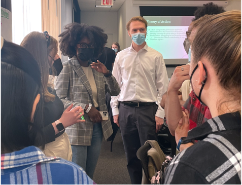 Students standing and talking in a small group during a student-led activity in Seminar