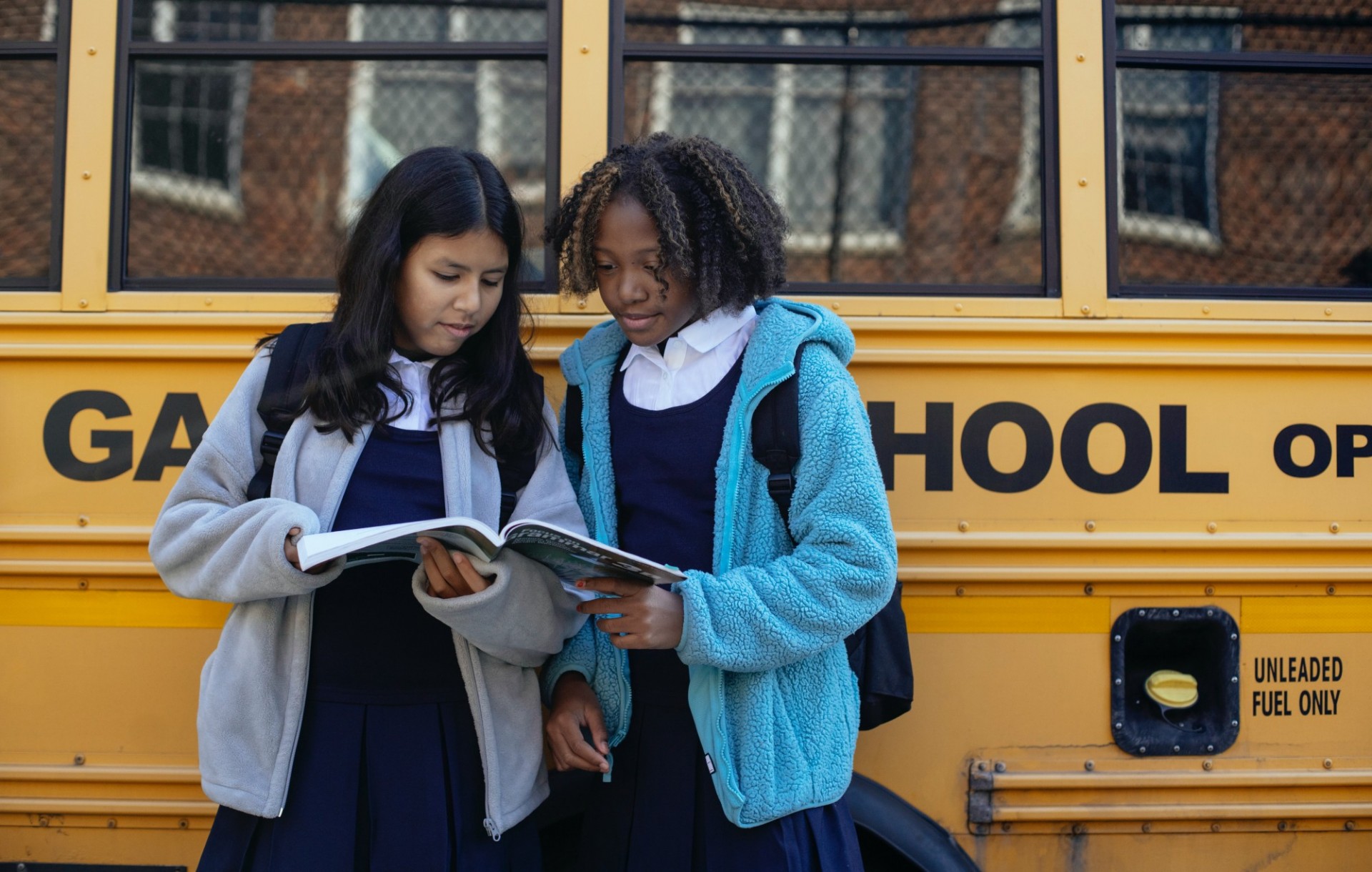 Students looking at a book in front of a school bus