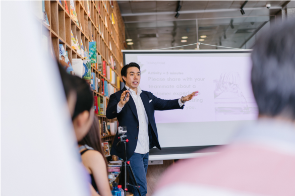 Male facilitator in front of a whiteboard, leading a training session with adult attendees