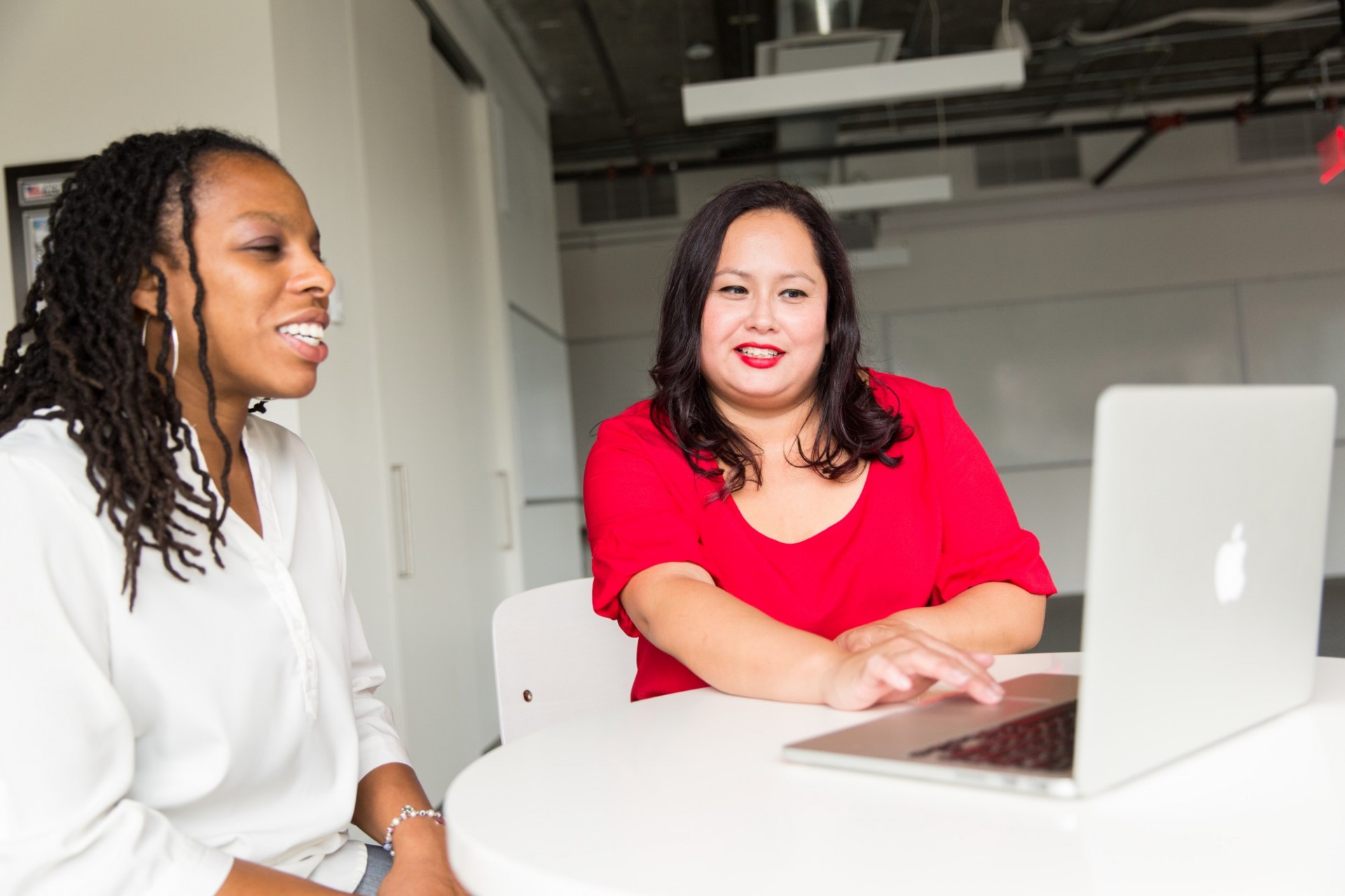 Two women seated around a laptop, smiling