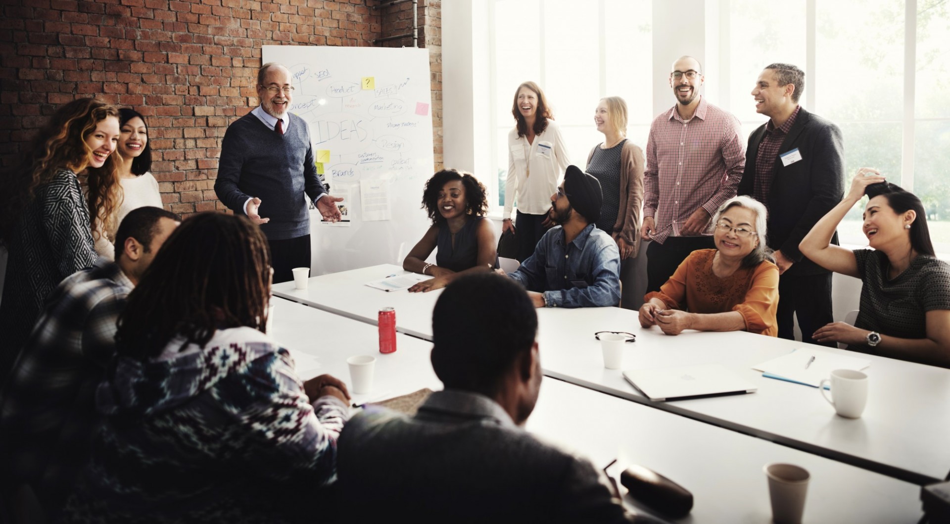 Cover image from Leading Through Learning which features a group of adults seated and standing around the table. The group reflects a diversity of races, ethnicities, genders, and ages.